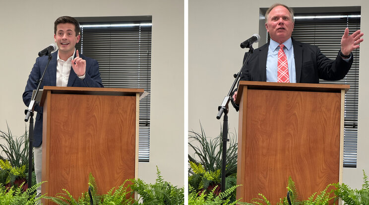 two men standing at a podium speaking